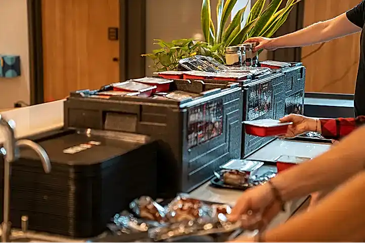 Sıcak yemeklerini kutulardan alan kişiler görseli